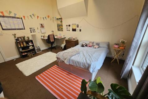 A cozy bedroom featuring a double bed with a li...