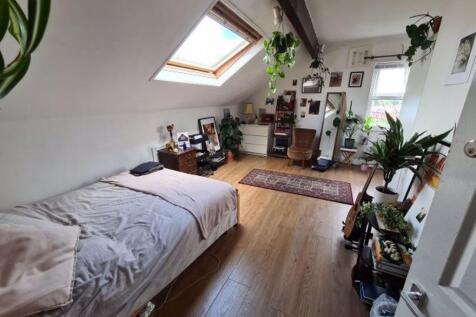 A bright and cozy bedroom featuring a large bed...