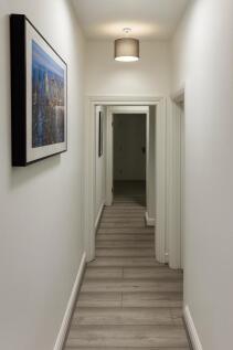 Bright, neutral hallway with modern pendant lig...
