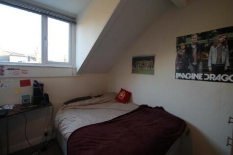 A cozy bedroom featuring a single bed with a be...