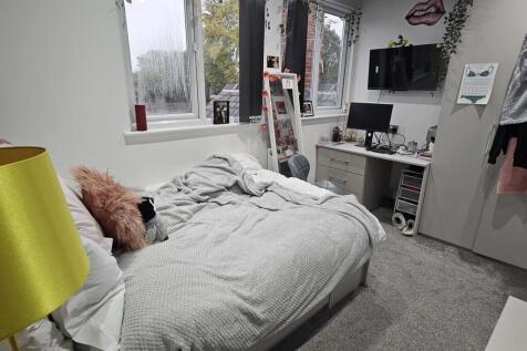 A bright and tidy bedroom featuring a comfortab...