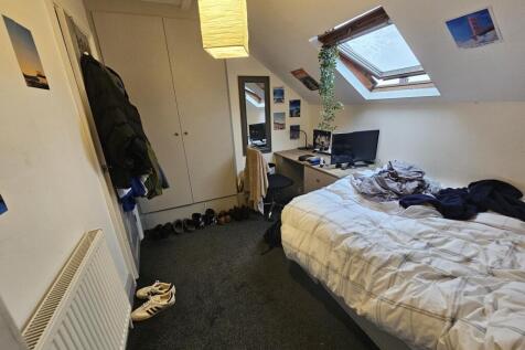 A cozy bedroom featuring a single bed positione...