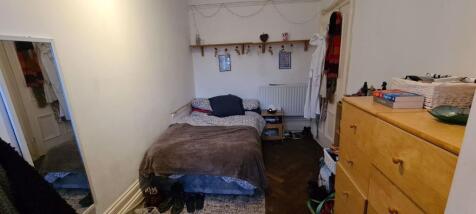 A modest bedroom featuring a single bed, a smal...