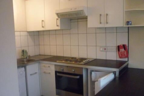 A compact kitchen area featuring white cabinetr...