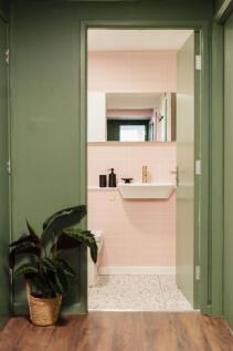 A stylish and bright bathroom with soft pink ti...