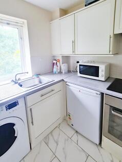 Bright fitted kitchen with a large window, stai...