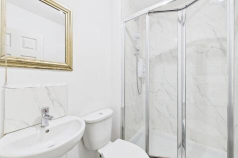 A modern, clean bathroom featuring a corner sho...