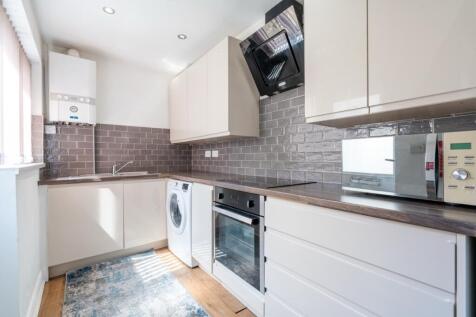 Modern kitchen with sleek white cabinetry, stai...