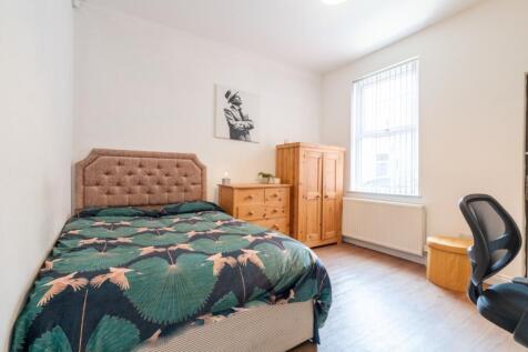 A cozy bedroom featuring a plush upholstered he...