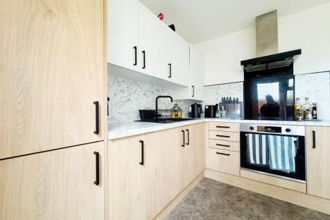 Modern L-shaped kitchen with light wood lower c...