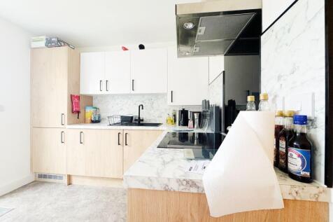 Bright modern kitchen with light wood cabinets,...