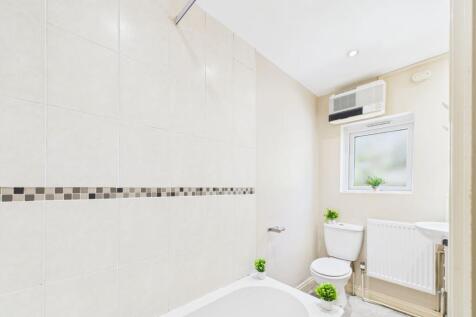 Bright and clean bathroom featuring a bathtub w...