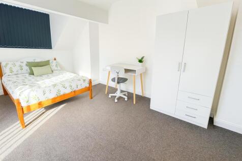 A bright and tidy bedroom featuring a comfortab...