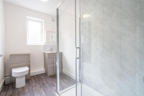 A clean and modern bathroom featuring a walk-in...
