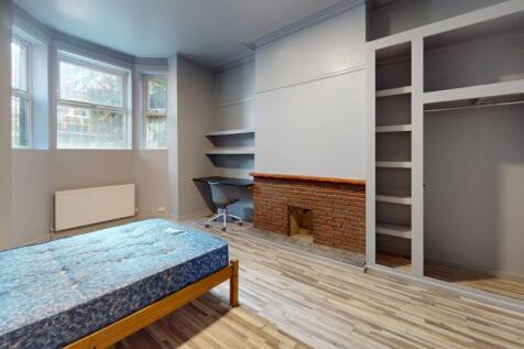 A well-lit bedroom featuring a large window, a ...