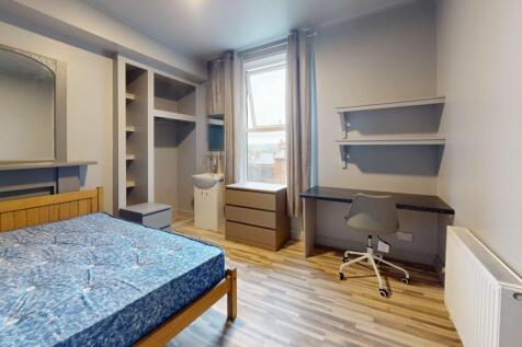 A well-lit single bedroom featuring a wooden be...