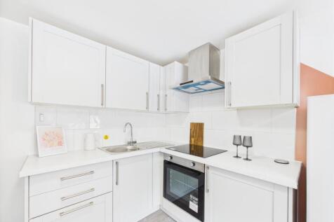 Bright modern white kitchen with integrated ove...