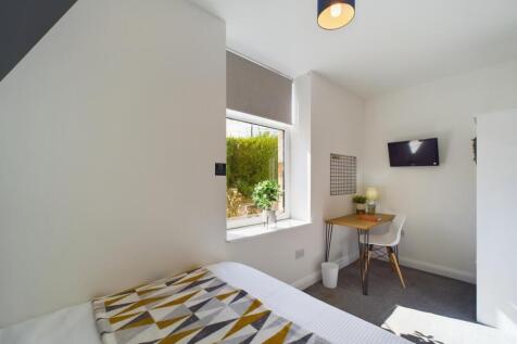 A bright and tidy bedroom featuring a comfortab...