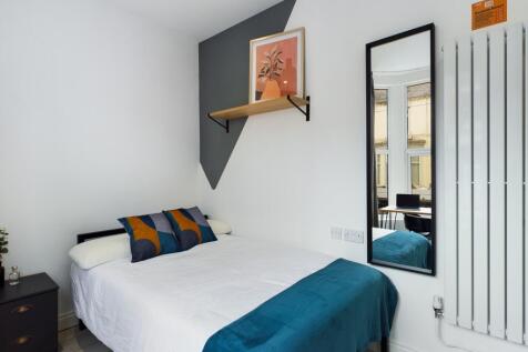 A bright and inviting double bedroom with styli...