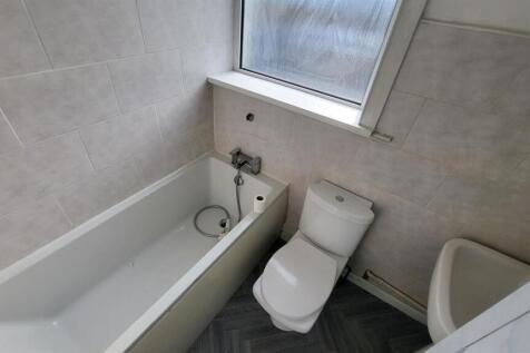 Clean, modern bathroom with a white bathtub, cl...