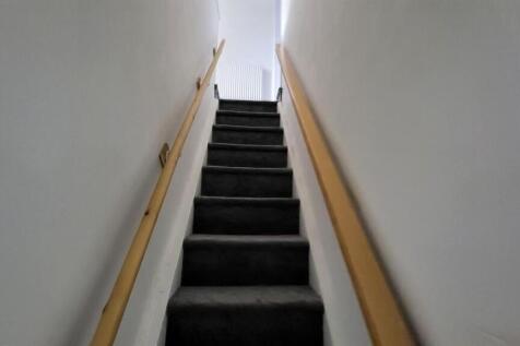 Narrow carpeted staircase with light-colored wa...