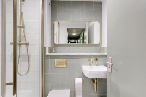 Light, modern bathroom with tiled walls, a wall...