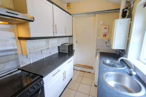Bright galley kitchen with white cabinets, blac...