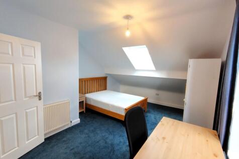 Bright attic double bedroom with a wooden bed f...