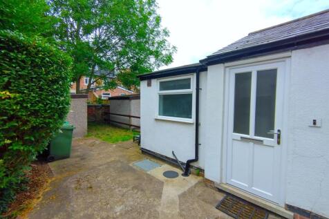 Neat paved rear yard with a white back door, fe...