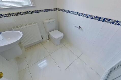 Bright, modern white tiled bathroom with a pede...