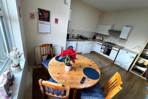 Bright open kitchen-diner with a round wooden t...