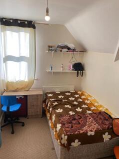 A cozy single bedroom featuring a bed with flor...