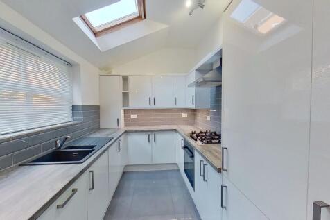 Bright modern galley kitchen with gloss white c...