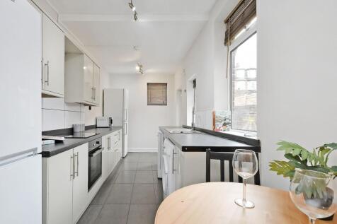 Bright, modern galley kitchen with white cabine...