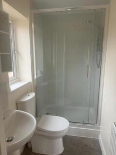 Bright, modern bathroom with a large glass-encl...