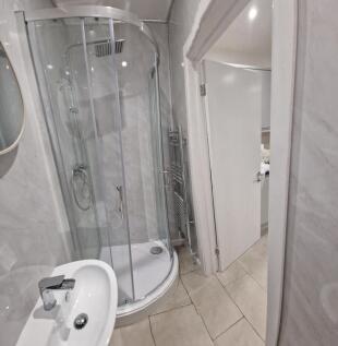 Modern tiled bathroom with a curved glass showe...