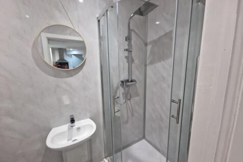 Bright modern bathroom with a corner glass show...