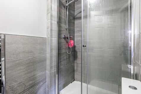 Modern tiled bathroom with a glass-enclosed wal...