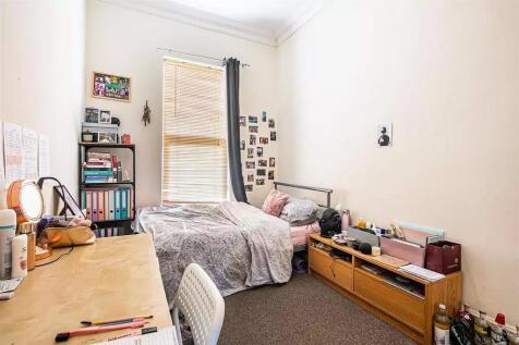 A cozy single bedroom featuring a comfortable b...