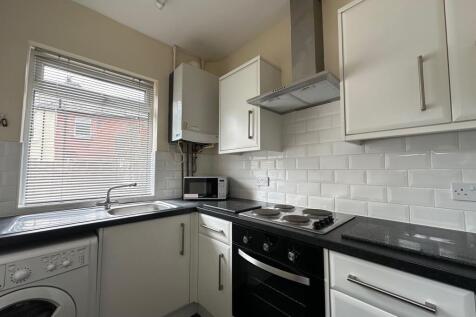 Bright, modern kitchen with white cabinetry, bl...