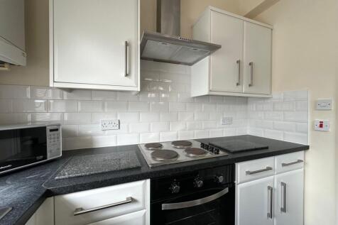 Bright modern kitchen with white cabinets, tile...