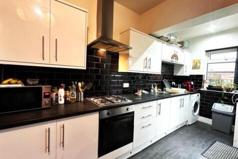 Bright modern kitchen with white cabinetry, bla...
