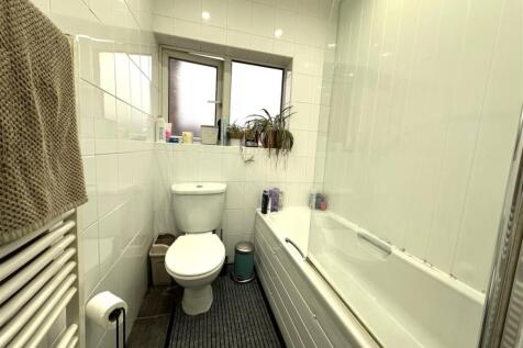 Bright, modern bathroom with white tiled walls,...