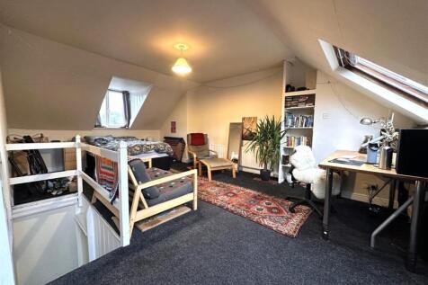 Spacious loft bedroom with sloped skylight wind...