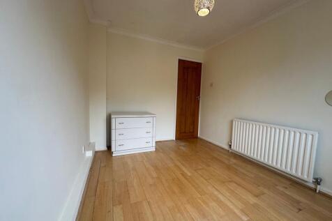 Bright, neutral single bedroom with light wood ...