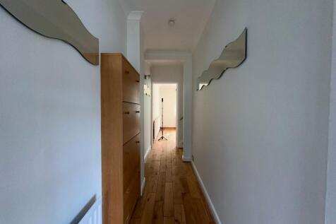 Bright, narrow hallway with wooden floorboards,...