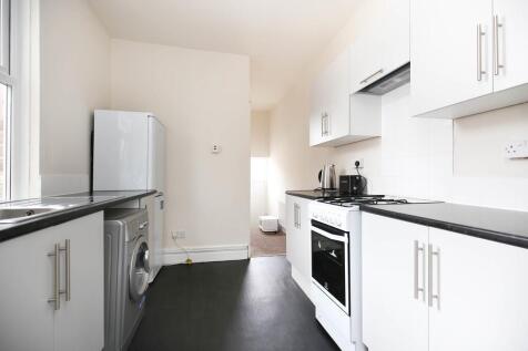 Bright, modern galley kitchen with white cabine...