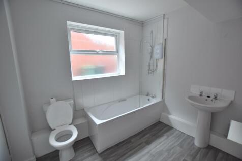 Bright, simple bathroom with a white bathtub an...
