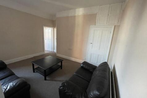 Bright neutral living room with two black leath...