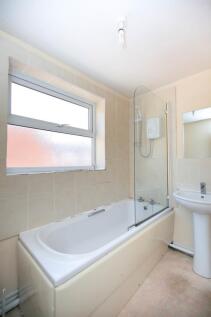 A bright and tidy bathroom featuring a bathtub ...